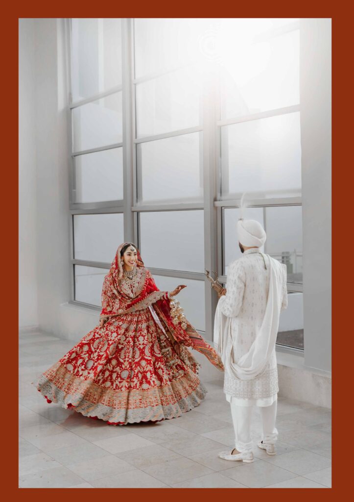Bride in a red lehenga twirling in a bright window-lit room, South Florida Sikh wedding