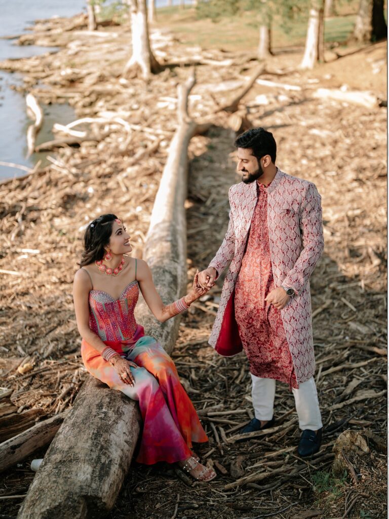 Priya & Dillan’s Gujarati Wedding | Indian Wedding Photographer Atlanta 2 Indian couple in pink outfits sitting on driftwood by a lake for their Atlanta engagement photos
