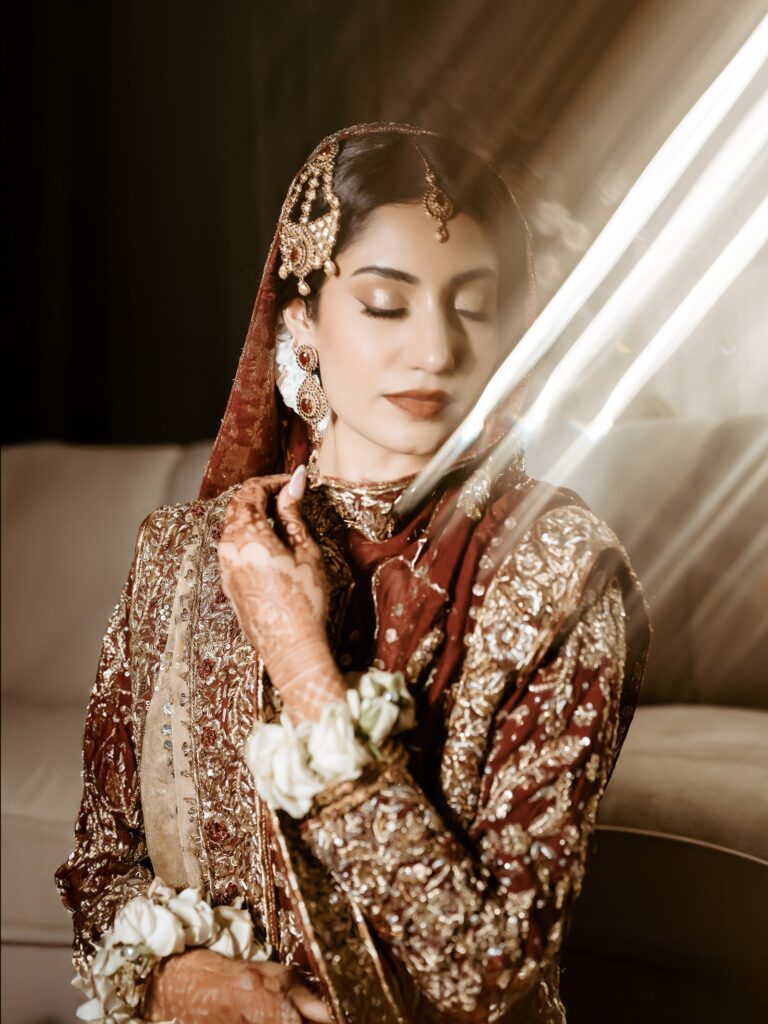 Amen & Shoaib’s Stunning South Asian Wedding at Signia by Hilton & Waldorf Astoria Orlando 19 Bride in maroon and gold with a jhoomar and gold jewelry, shaadi portrait in Orlando