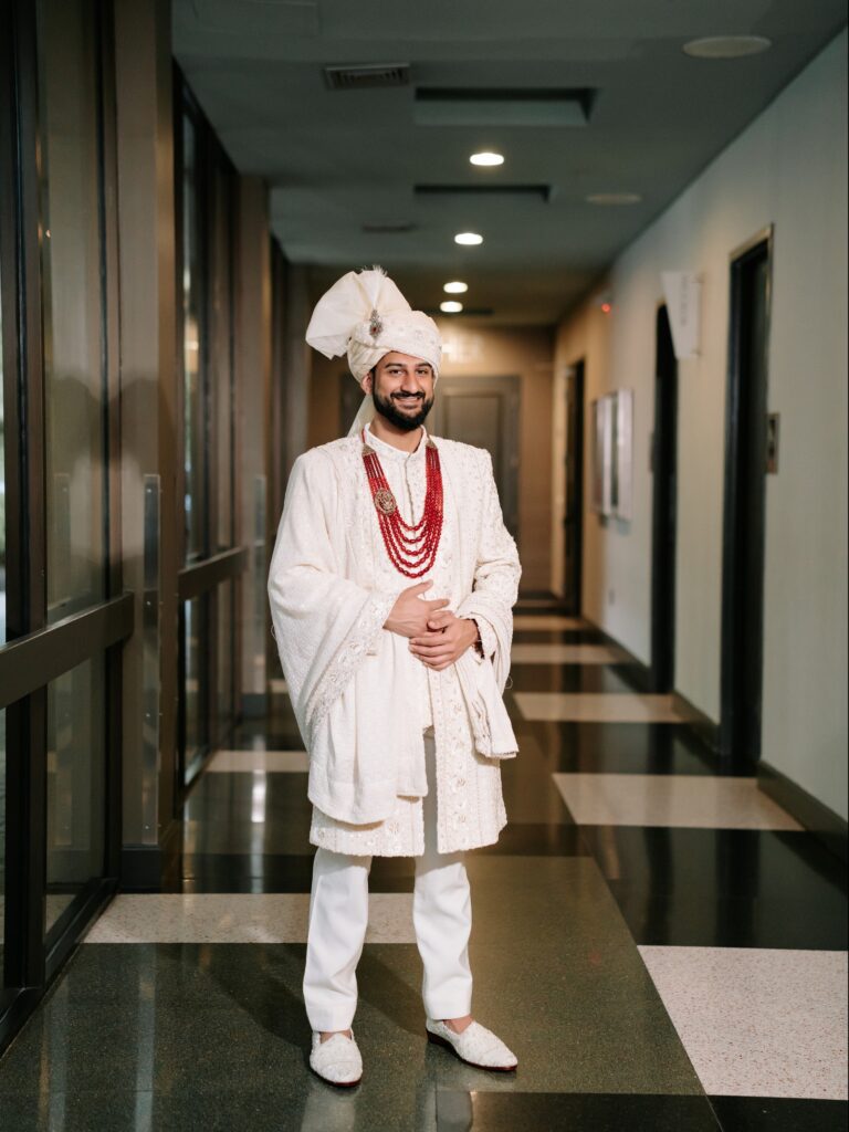 Priya & Dillan’s Gujarati Wedding | Indian Wedding Photographer Atlanta 9 Gujarati groom in an ivory sherwani, safa and red beaded mala in a hotel hallway on his wedding morning