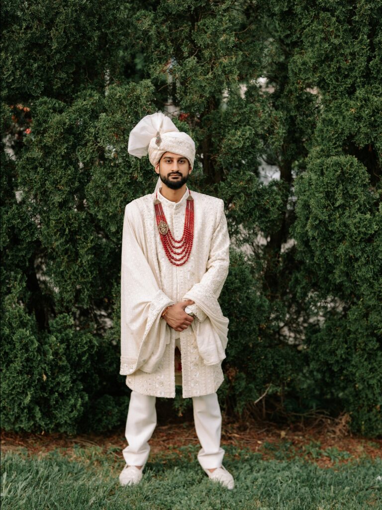Priya & Dillan’s Gujarati Wedding | Indian Wedding Photographer Atlanta 11 Indian groom in an ivory sherwani and safa standing in front of evergreen trees on his wedding day