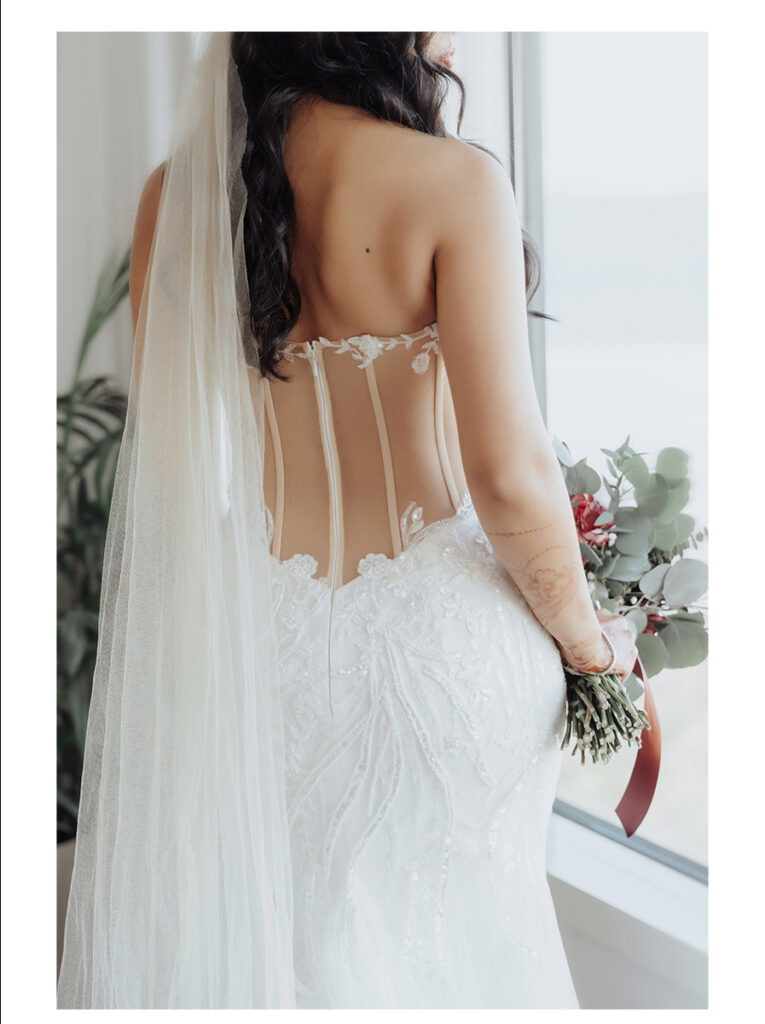 Shobin & Maria’s Malayali Christian Wedding at Grand Hyatt Tampa Bay 4 Back of a sheer corset lace wedding gown with a long veil and a eucalyptus and red rose bouquet, Malayali Christian bride in Tampa