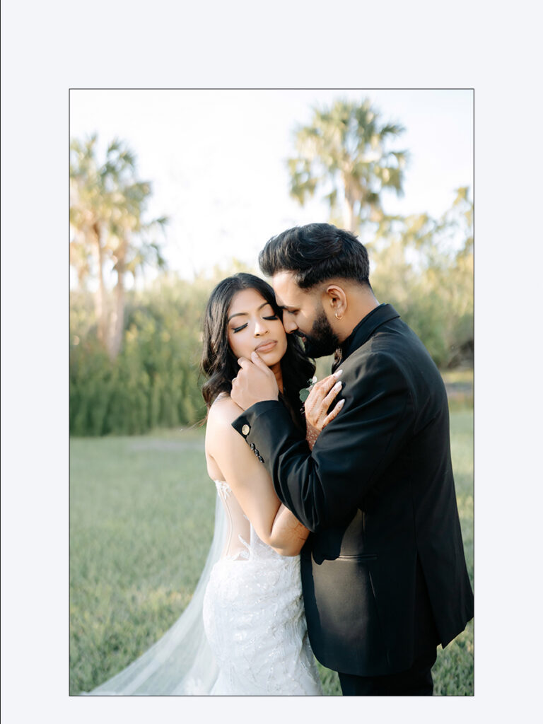 Shobin & Maria’s Malayali Christian Wedding at Grand Hyatt Tampa Bay 6 Groom in a black tuxedo holding the bride close under palm trees, Malayali Christian wedding in Tampa by Noor K Photography