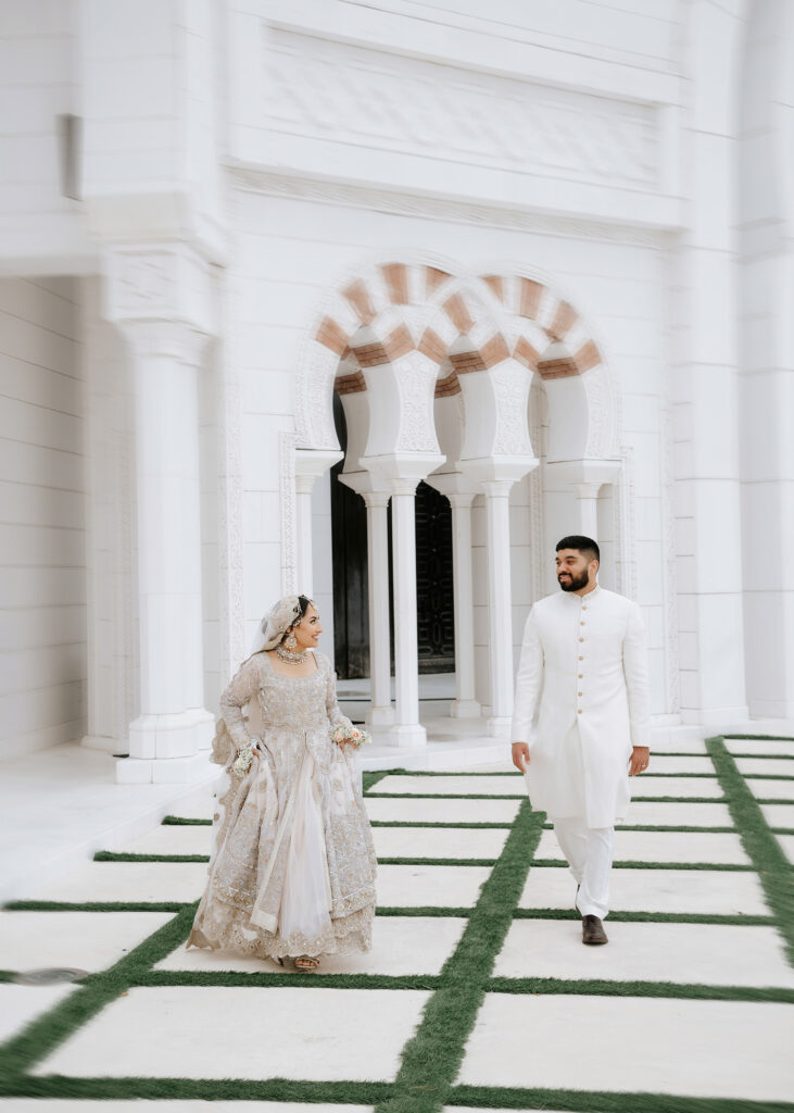 Bride and groom walking past white Moorish arches at Masjid Al-Hayy, Muslim wedding photographer Orlando Noor K Photography