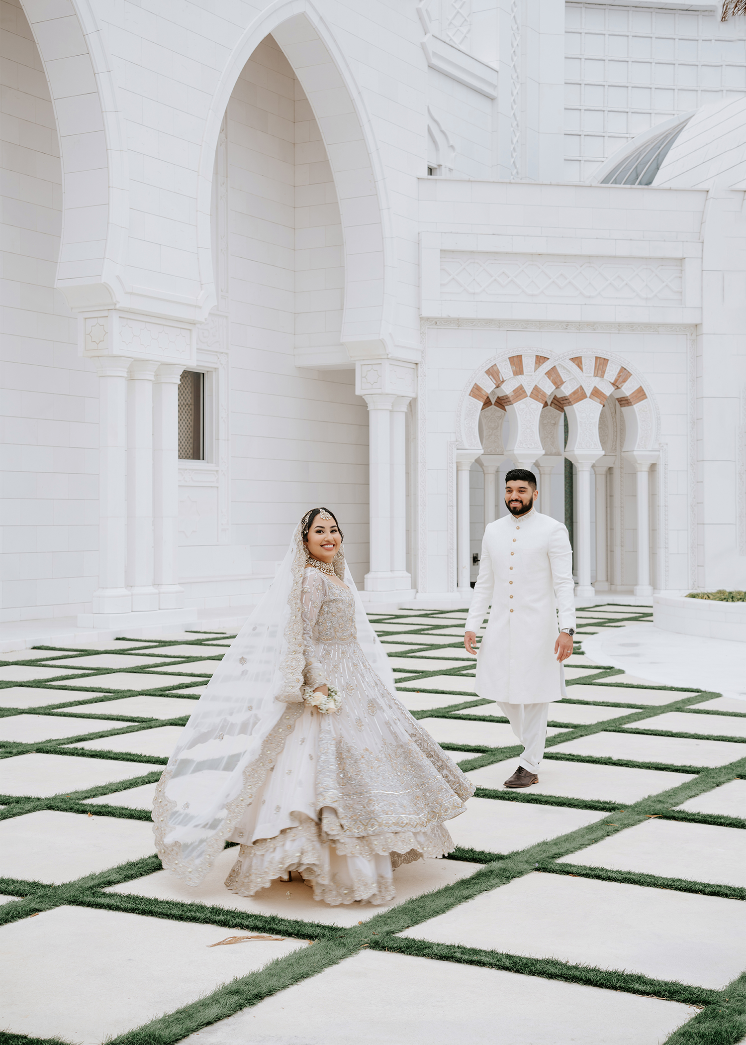 Bride twirling her silver lehenga in the courtyard of Masjid Al-Hayy as the groom in a white sherwani walks toward her, Orlando nikah photographer