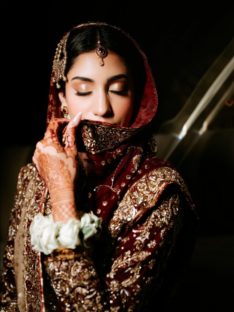 Amen & Shoaib’s Stunning South Asian Wedding at Signia by Hilton & Waldorf Astoria Orlando 20 South Asian bride holding her red dupatta across her face with mehndi hands and white gajray, Orlando