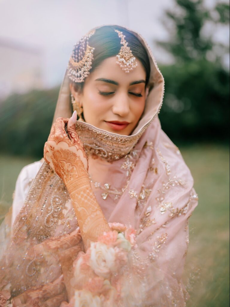 Amen & Shoaib’s Stunning South Asian Wedding at Signia by Hilton & Waldorf Astoria Orlando 8 South Asian bride with mehndi-covered hands holding her embroidered blush dupatta, eyes closed