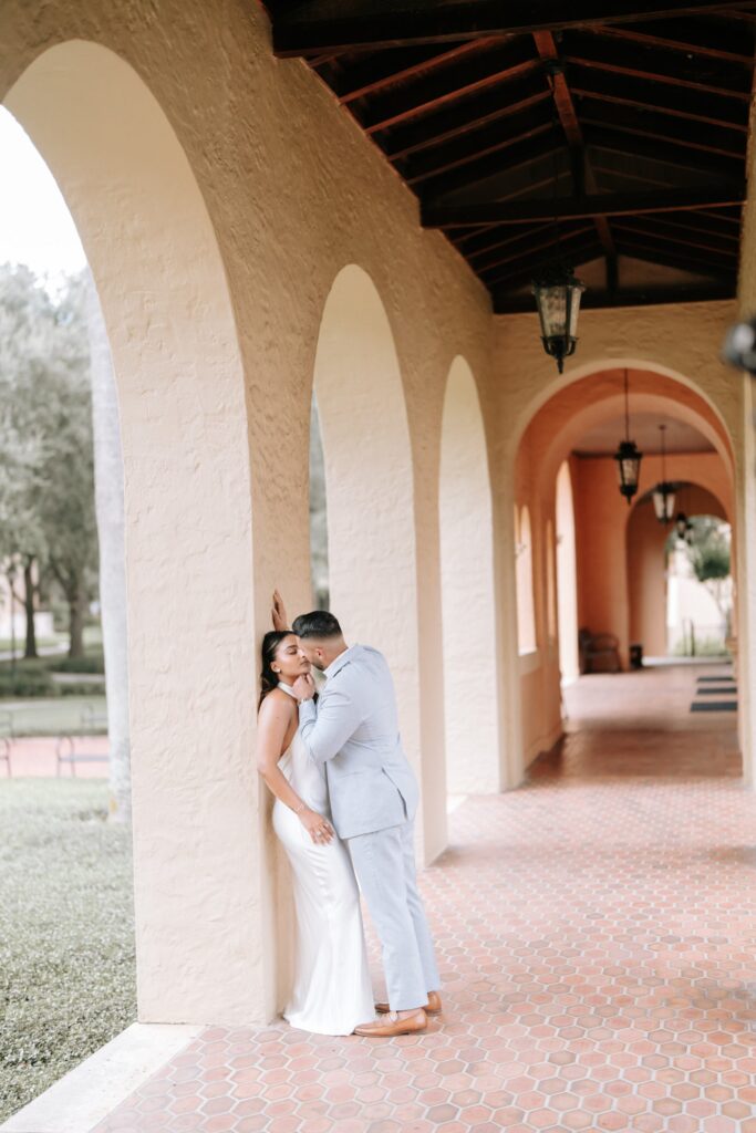 Rahul & Nirali’s Romantic Rollins College Engagement Session 9 Couple sharing a kiss in an arched loggia with terracotta tile floors, Rollins College