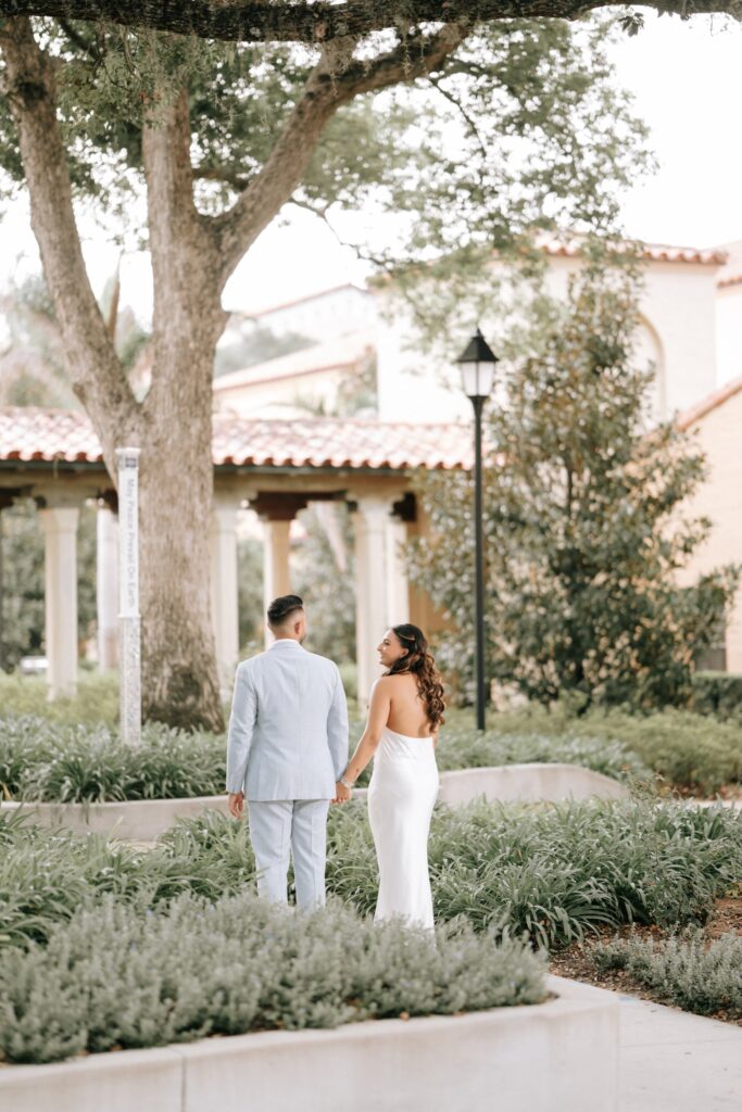 Rahul & Nirali’s Romantic Rollins College Engagement Session 11 Couple walking hand in hand through a garden toward a tiled colonnade at Rollins College