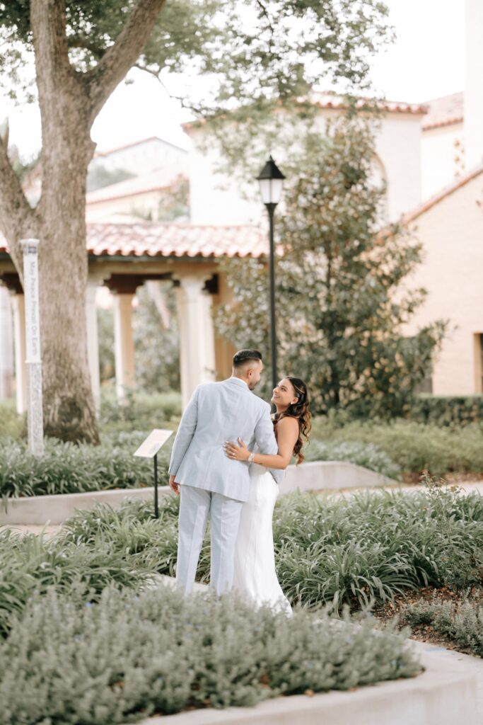 Rahul & Nirali’s Romantic Rollins College Engagement Session 13 Bride-to-be looking back at her fiancé in a garden on the Rollins College campus