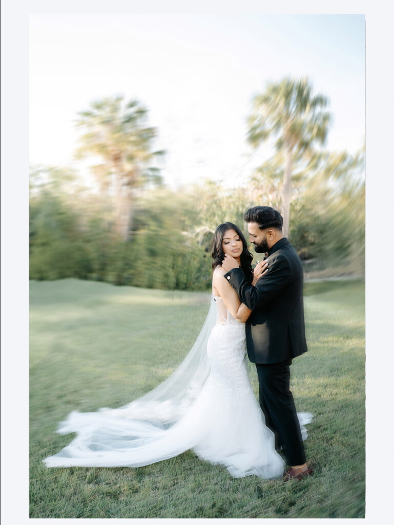 Shobin & Maria’s Malayali Christian Wedding at Grand Hyatt Tampa Bay 7 Bride with a long cathedral veil and the groom embracing on the lawn among palm trees at golden hour in Tampa