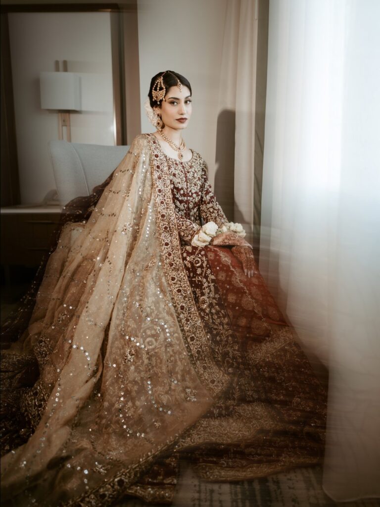 Amen & Shoaib’s Stunning South Asian Wedding at Signia by Hilton & Waldorf Astoria Orlando 18 South Asian bride in a maroon and gold bridal lehenga with white flower wrist gajray in her hotel suite
